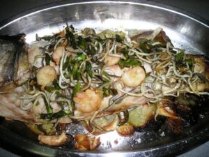 Lubina salvaje en cama de verduras cubierta de mar y tierra